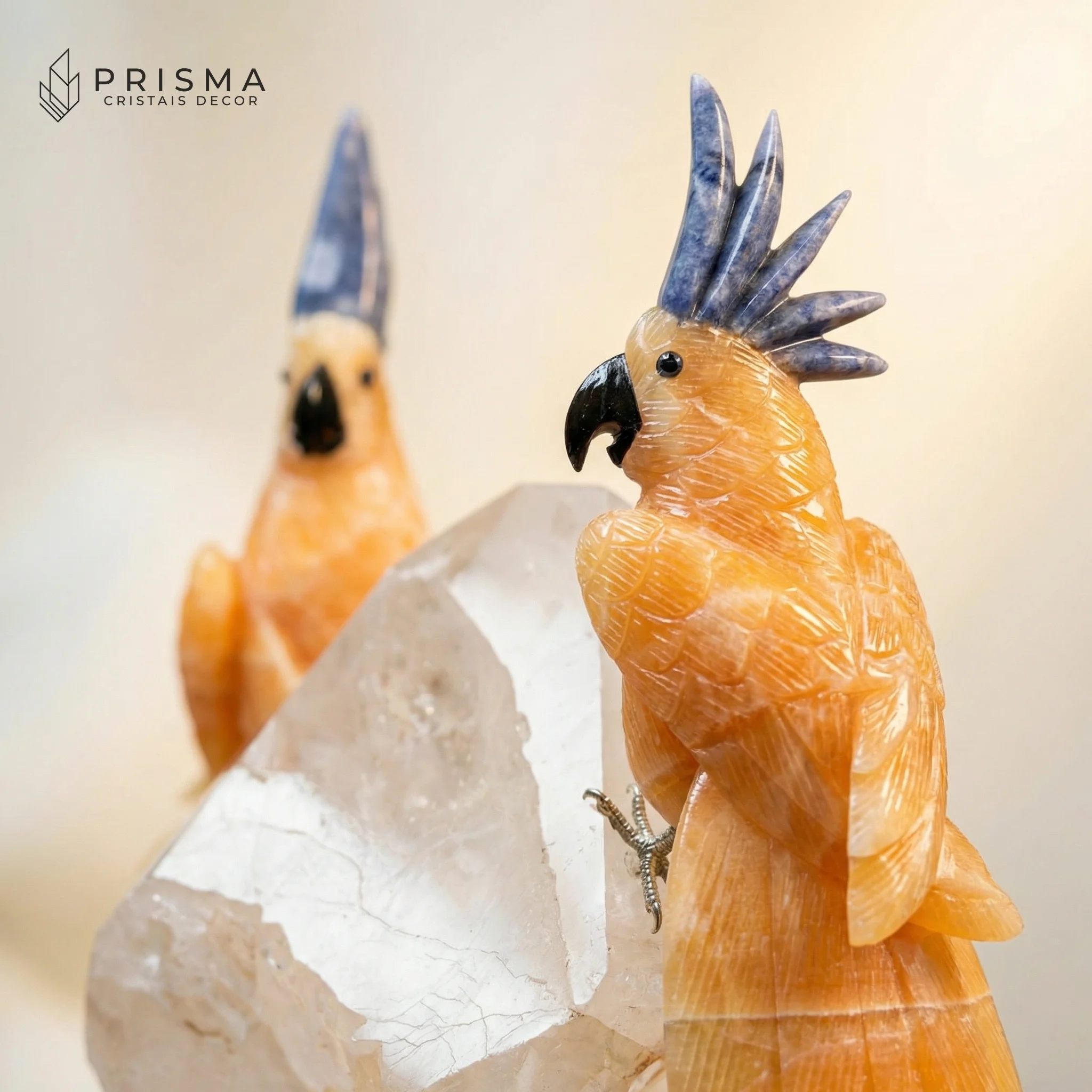 Detalhe artesanal das cacatuas esculpidas em calcita laranja mexicana com penacho em sodalita azul, close premium