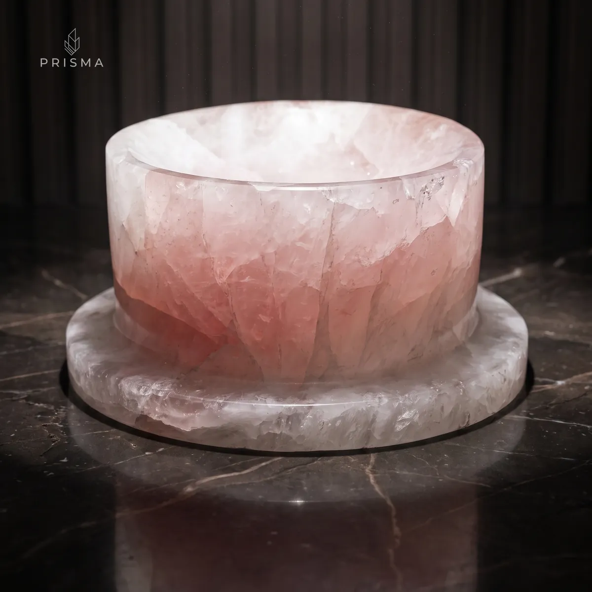 Comedouro de pedra em quartzo rosa com borda branca translúcida sobre piso de mármore escuro